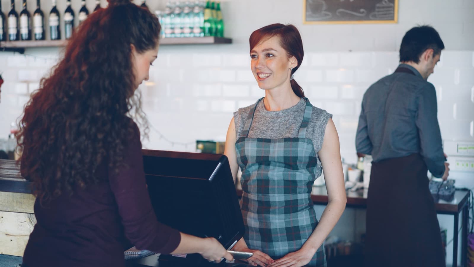 Kafe tezgâhında müşterisine gülümseyen barista