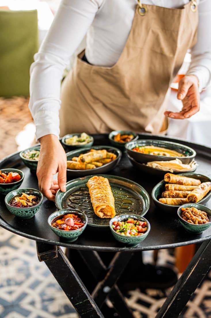 Garson, meze tabaklarıyla dolu tepsiyi masaya servis ediyor